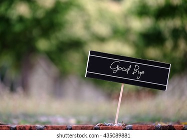 Word Quotes Of GOOD BYE On Card Board Against Blurred Green Background. Selective Focus.