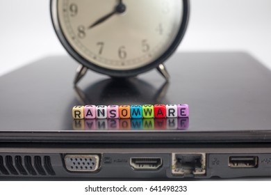 Word RANSOMWARE On Dice Over Laptop With Blurry Clock.virus Threat Concept