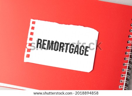The word remortgage on torn paper on red notepad,.