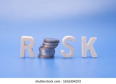 The Word Risk With Stack Coins,isolated Over Blue,financial Risk Concept.