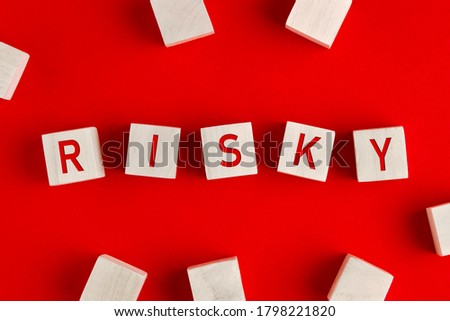 The word risky written on wooden blocks on red background. Concept of risk management or assessment and decision making in an uncertain business environment.