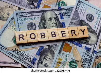 The Word Robbery On Dollar Usa Background. Theft And Stealing Money Concept