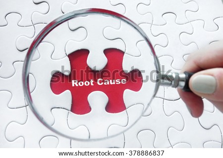 Word Root Cause with hand holding magnifying glass over jigsaw puzzle