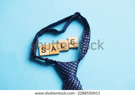 the word sale made by wooden cubes on a blue background with a tie