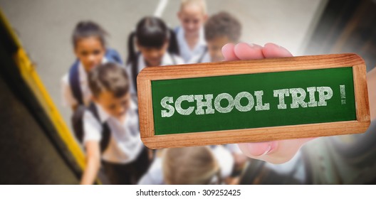 The Word School Trip! And Hand Showing Chalkboard Against Cute Schoolchildren Getting On School Bus