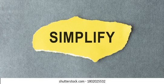 Word Simplify Written On A Yellow Piece Of Paper.