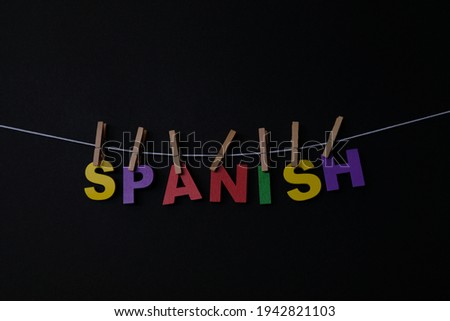 Word Spanish on black background. A Romance language spoken in Spain and in much of Central and South America.