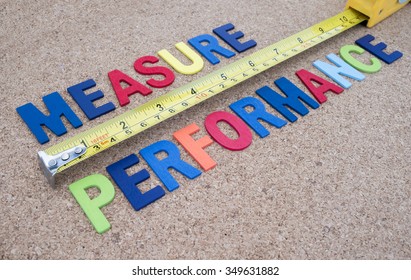 Word spelling "Measure Performance" and measuring tape on cork board background