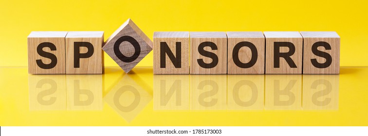 The word of SPONSORS on wood tiles concept. Word SPONSORS is made of wooden building blocks lying on the table and on a light yellow background. Concept