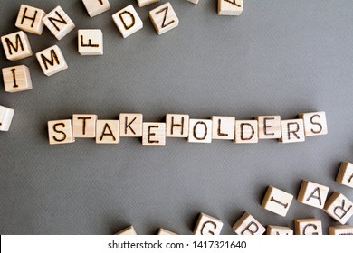 the word stakeholder wooden cubes with burnt letters, business development in favor of shareholders gray background top view, scattered cubes around random letters