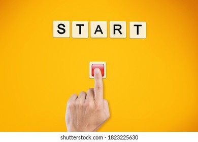 The word start on wooden cubes with a male hand pressing the start button.