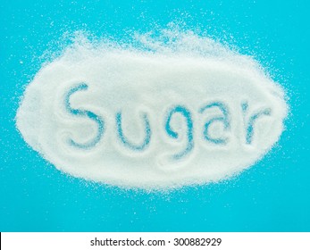 The word sugar written into a pile of granulated sugar on blue background. top view - Powered by Shutterstock