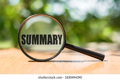 The word Summary on magnifier glass on wooden table. Business concept.
