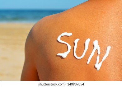 The Word Sun Written With Sunblock On The Back Of A Man Who Is Sunbathing On The Beach