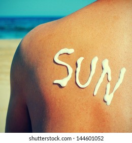 The Word Sun Written With Sunblock On The Back Of A Man Who Is Sunbathing On The Beach, With A Retro Effect