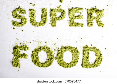 Word Superfood Piled Of 
Green Powder Of Barley Grass On White Background.