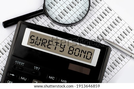 Word SURETY BOND on calculator. Business and tax concept.
