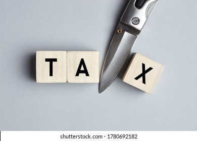 The Word Tax Cut Written On Wooden Cubes With A Knife. Tax Cut, Reduction Or Deduction Concept.