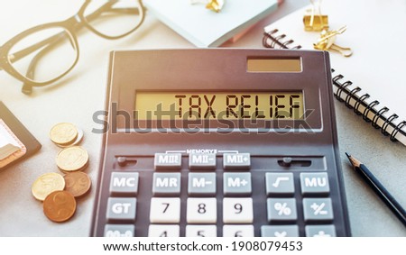 Word TAX RELIEF. Written on a calculator on an office desk.