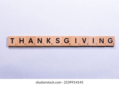 The word "Thanksgiving" spelled out with wooden letter tiles on a plain white background. - Powered by Shutterstock