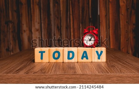 The word today. The word today written in english language on wooden blocks with a red clock in the image composition. Close-up photo. Concepts of starting projects, achieving success and doing now.