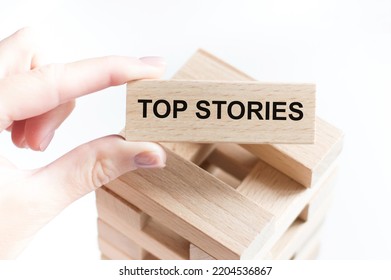 The Word Top Stories On A Wooden Bar In A Man's Hand