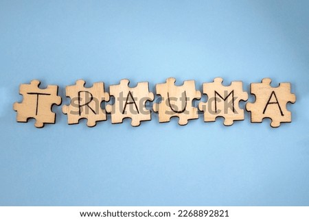 The word TRAUMA wooden written on the puzzles on a blue background