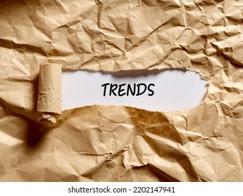 The Word Trends Written Under A Brown Torn Paper. Discovering The Current Popular Trends Concept.