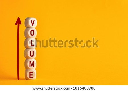 The word volume on stacked wooden cubes with arrow. Increasing music volume or production quantity or capacity in business concept. 