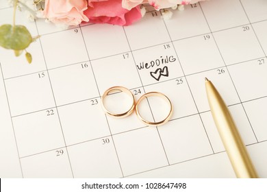 Word wedding, two hearts and gold rings on calendar with sweet rose bouquet. Love, invitation, advertisement, romantic background concept, copy space - Powered by Shutterstock