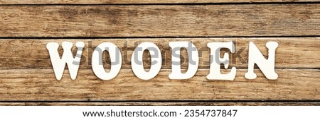 The word Wooden written on wood letters on wooden background, top view.