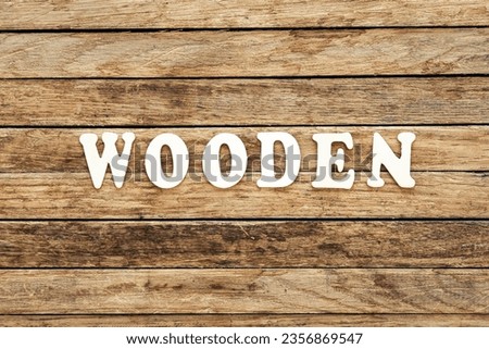 The word Wooden written on wood letters on wooden background, top view.