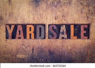 The word "Yard Sale" written in dirty vintage letterpress type on a aged wooden background.