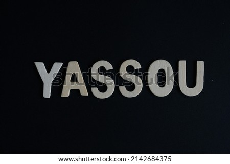 Word 'Yassou' on black background. Yassou is the word for Greek say Hello or greetings.