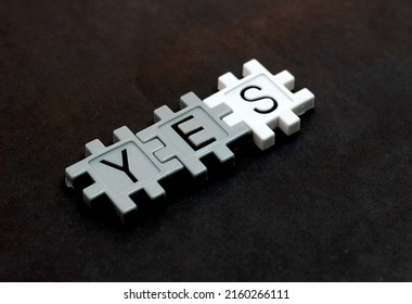 The word YES is composed using a plastic puzzle lying on a table and on a black background.