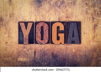 The word "Yoga" written in dirty vintage letterpress type on a aged wooden background.