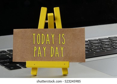 Wording Today Is Pay Day On Mini Stand With The Laptop Background. Greeting And Business Concept.