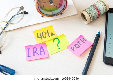 Words 401k ira roth on pieces of colorful paper, money dollars and glasses on table. Pension concept. Retirement plans.