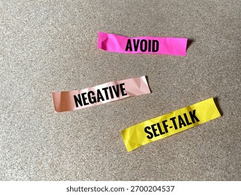 The words 'AVOID', 'NEGATIVE', and 'SELF-TALK' written on three separate pieces of brightly coloured crumpled paper.