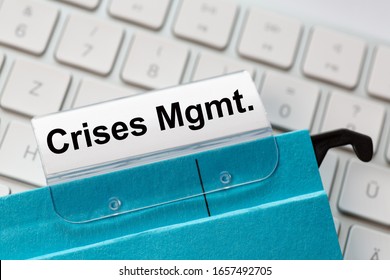 The Words  Crises Management Can Be Seen On The Label Of A Blue Hanging Folder. The Hanging Folder Is On A Computer Keyboard.