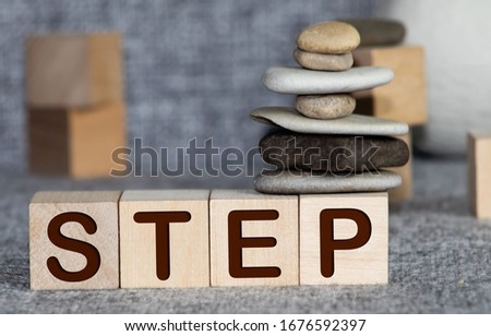 The words Next Step on small wooden dices on a table, close up shot, view from above
