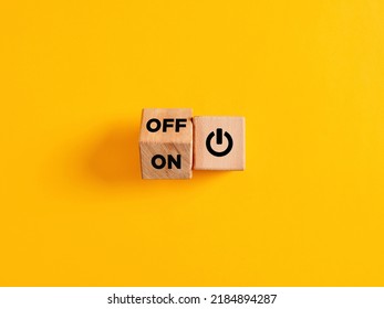 The words on and off on wooden cubes with start icon on yellow background. Power on off switch or start and stop button concept.
