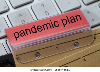 The words  pandemic plan can be seen on the label of a brown hanging folder. The hanging folder is on a computer keyboard. - Shutterstock ID 1655946511
