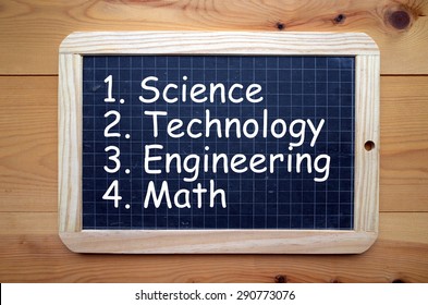 The Words Science, Technology, Engineering And Math In White Text On A Blackboard. These Are Known As The STEM Education Subjects