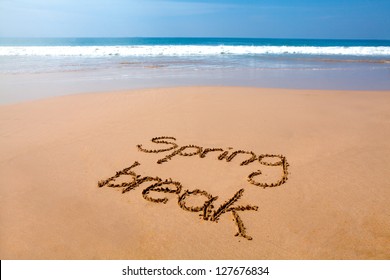 Words spring break written in sand on a tropical beach, with sea in background - Powered by Shutterstock
