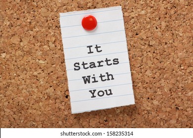The words It Starts With You typed on a scrap of lined paper and pinned to a cork notice board. A concept for customer service or self improvement, adapting to change or making plans.