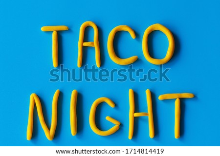 The words TACO NIGHT are made of clay on a blue background, flat lay. USA, Mexican holiday, background with text.
