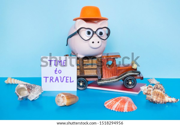 Words Time to travel, piggy bank and toy lorry on the\
blue background. 
