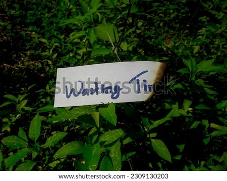 the words wasting time on burning paper on green grass
