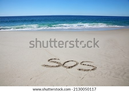 Words written in sand. The Initials S. O. S. written in the sand on the beach with the ocean background. S. O. S. are initials for the distress message Save Our Ship. Help. SOS. Save Our Ship. .  